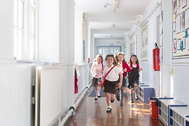 dziewczynki w galowych strojach biegnące szkolnym korytarzem